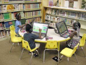 Young children sitting around a table with laptops